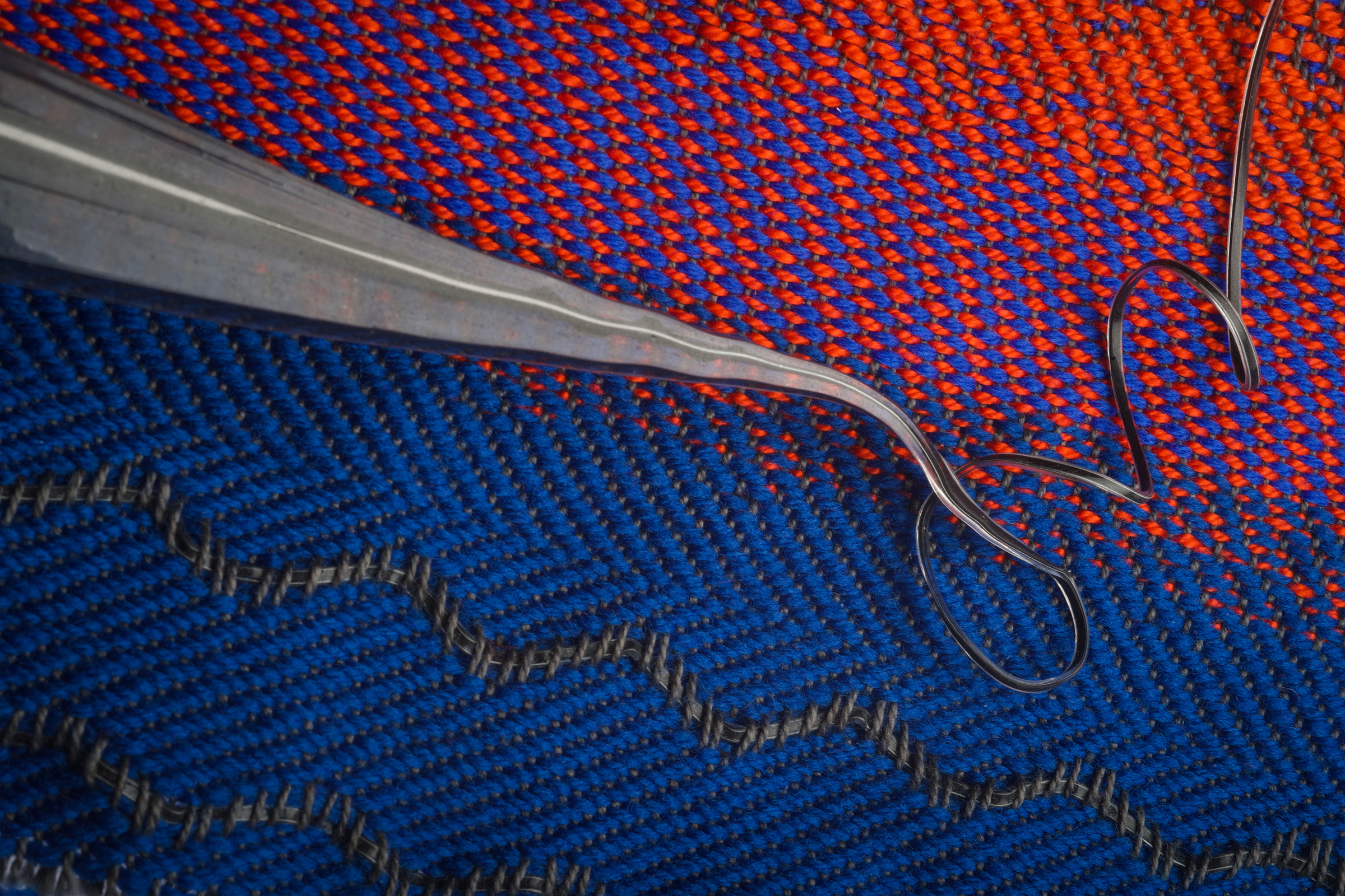 A grey acoustic fiber snakes across a background of blue and red fabric