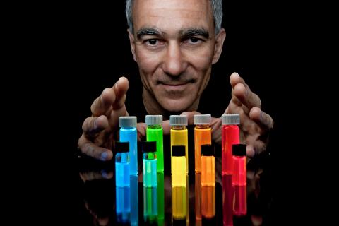 Prof. Moungi Bawendi behind a multicolored array of vials filled with luminescent quantum dots. (Photo: Len Rubenstein)