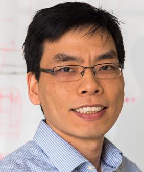 Prof. Zhang in front of a blurred wall of academic notes and equations